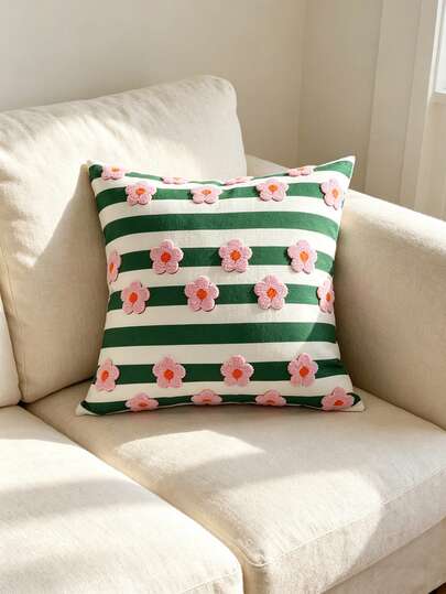 Green striped decorative pillow cover with pink daisy flowers on a cream armchair