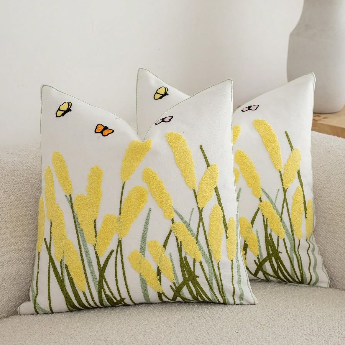 Ivory cushion cover with butter yellow textured meadow reeds, embroidered green stems, butterflies, and coordinating piping.
