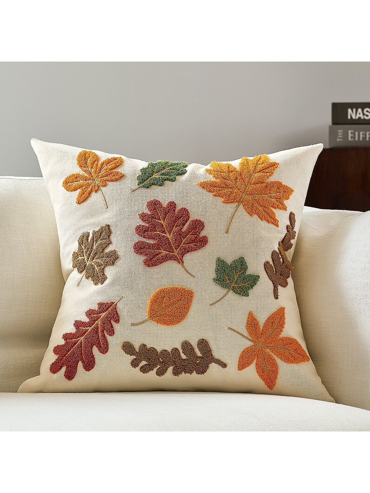 Autumn leaves tufted embroidered cushion cover in cream on white sofa with scattered maple, oak and chestnut leaf motifs in rust, orange, sage and brown