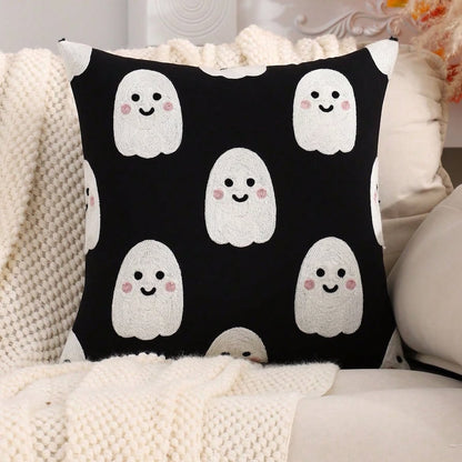 Cute ghost embroidered cushion cover in black with all-over white blushing ghost pattern on cream boucle sofa with fluffy white cushions and pink flowers