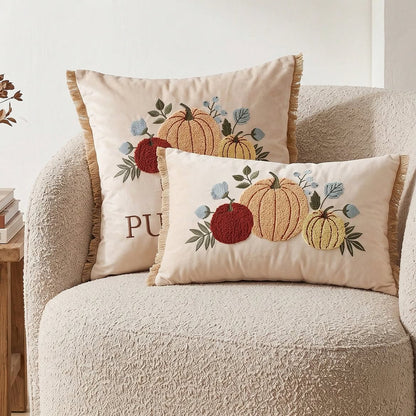 Pumpkin trio tufted embroidered cushion covers in cream canvas with golden fringe trim - square and lumbar sizes on cream boucle armchair