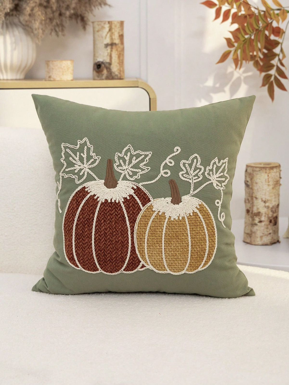 Embroidered pumpkin pillow cover in sage green background on sofa with autumn decor