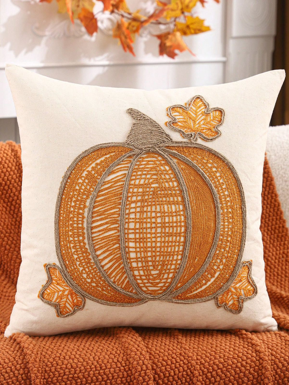 Lace embroidered pumpkin pillow cover in pumpkin orange with jute rope ribs and maple leaf accents on rust sofa