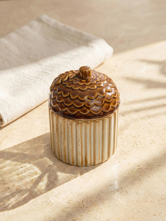 Ceramic acorn sugar bowl with lid on sandy linen surface in warm golden autumn light lifestyle shot
