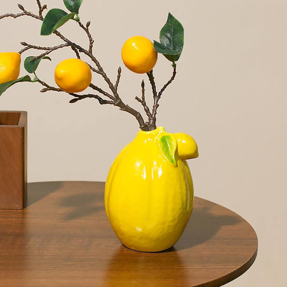 Yellow ceramic lemon-shaped vase with a branch of lemons. 