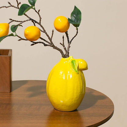 Yellow ceramic lemon-shaped vase with a branch of lemons. 