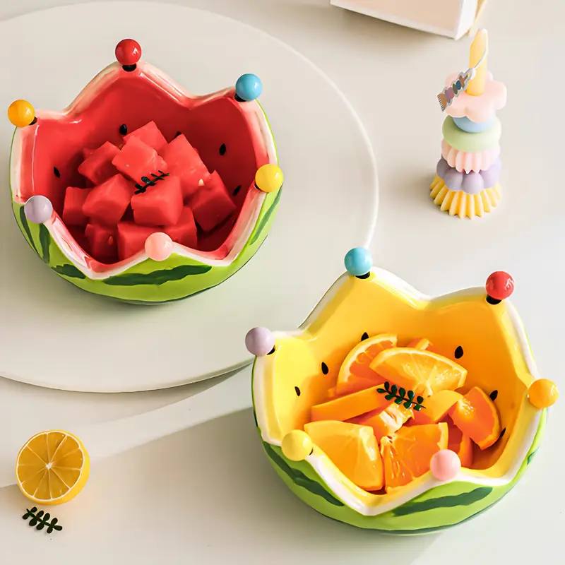 Two fruit-shaped bowls filled with watermelon and oranges.